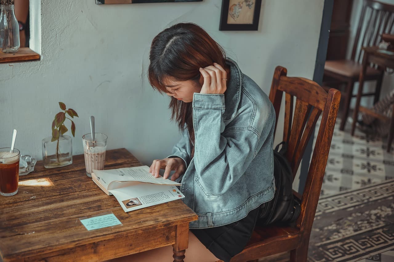 A woman reading at a wooden cafe table